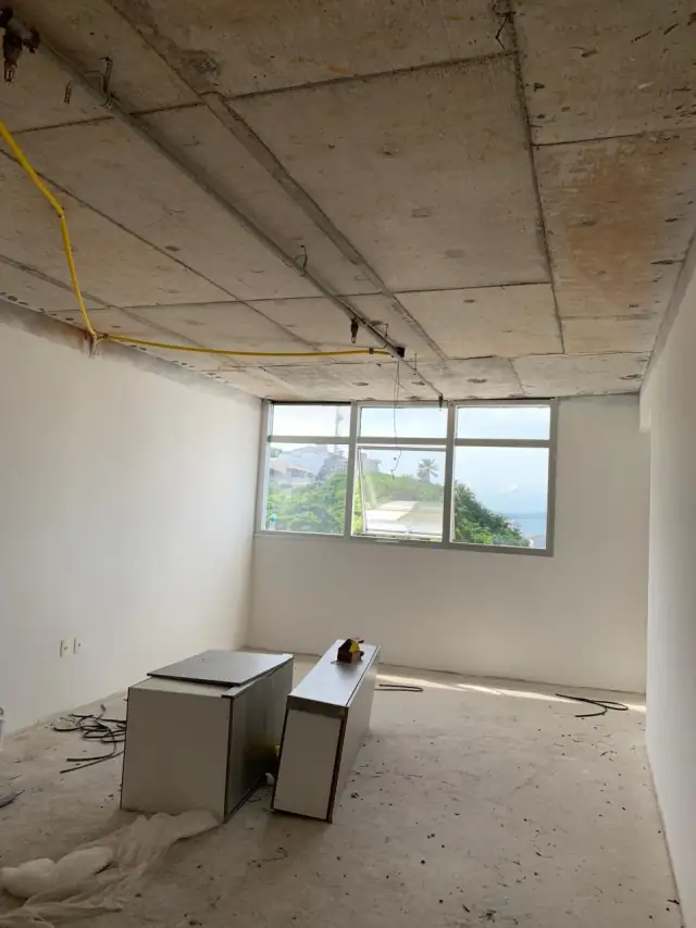 Sala com laje aparente e fiação solta, antes das divisões da clínica