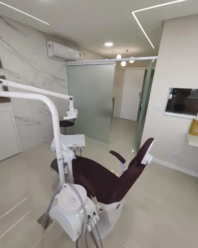 Consultório odontológico com porcelanato marmorizado e luz linear no forro