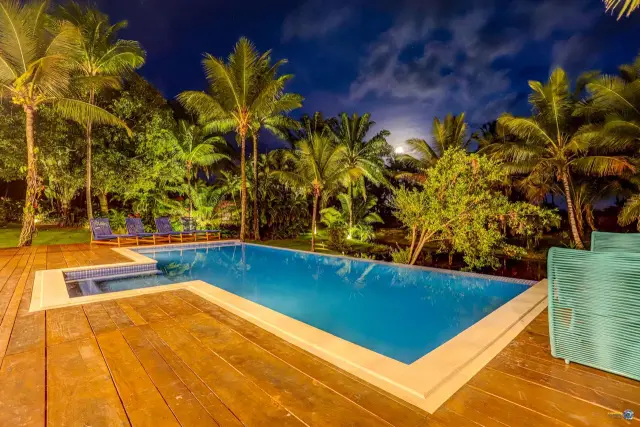 Deck e piscina iluminados à noite no Condomínio Txai, em Itacaré