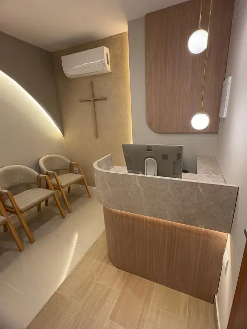 Recepção com parede curva em drywall, LED e balcão em pedra no escritório do Edifício Premier, em Ilhéus